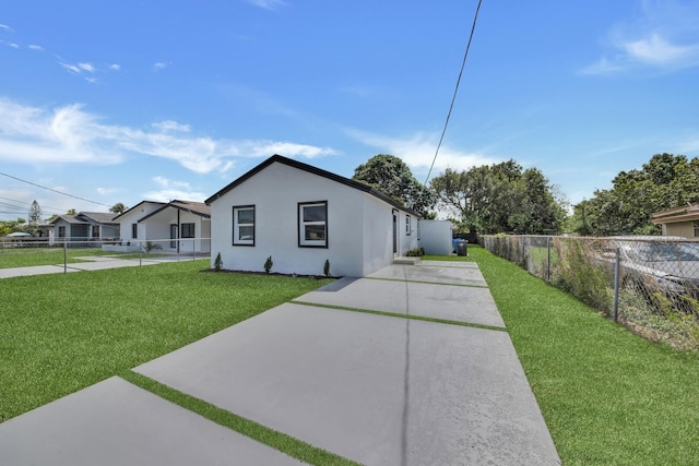 view of side of property featuring a yard, fence, and stucco siding