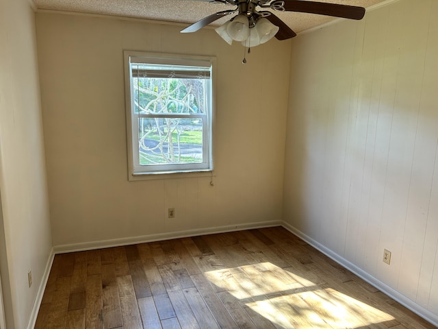 spare room with light wood-type flooring, ceiling fan, a textured ceiling, and baseboards