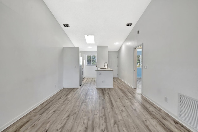 unfurnished living room with visible vents, light wood-type flooring, baseboards, and a sink