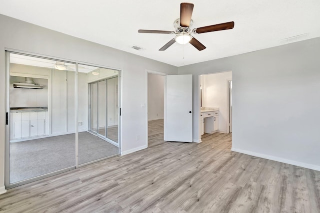 unfurnished bedroom featuring light wood finished floors, baseboards, visible vents, and a closet