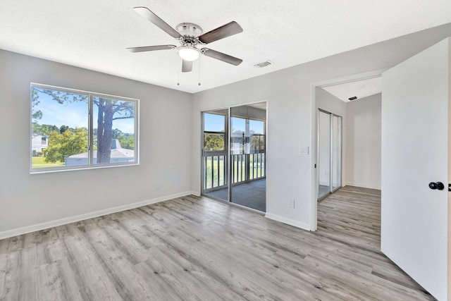 spare room featuring visible vents, a ceiling fan, baseboards, and wood finished floors