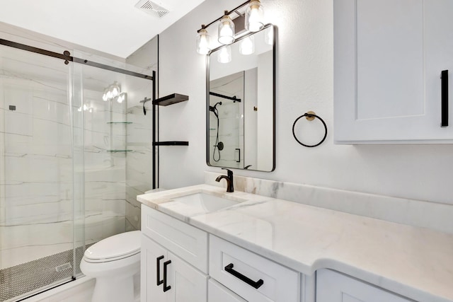 bathroom featuring a marble finish shower, visible vents, toilet, and vanity