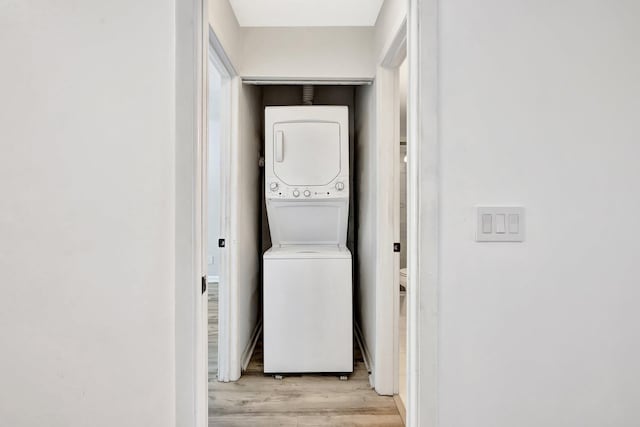 laundry room with light wood-type flooring, laundry area, and stacked washing maching and dryer