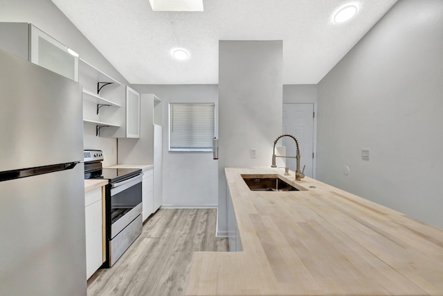 kitchen with open shelves, a sink, light countertops, white cabinets, and appliances with stainless steel finishes