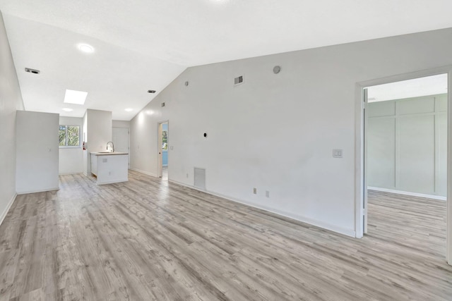 unfurnished living room with lofted ceiling, baseboards, visible vents, and light wood finished floors