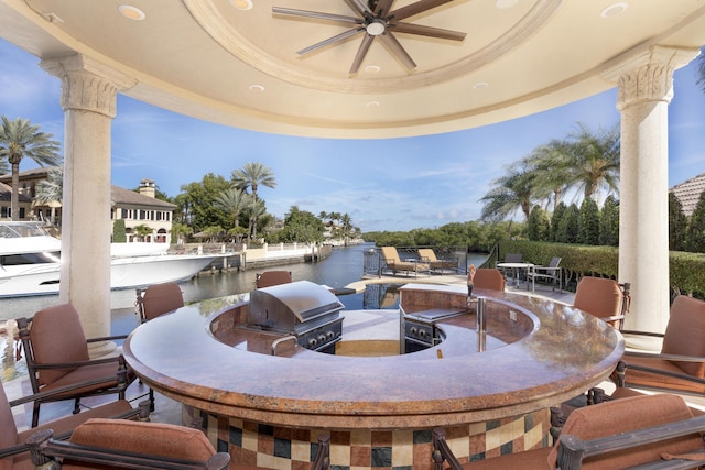 view of patio / terrace with ceiling fan, area for grilling, a water view, and exterior bar