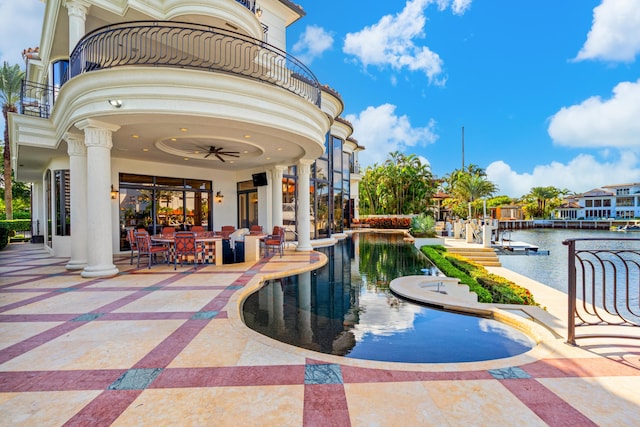 view of swimming pool with a patio, a water view, and ceiling fan