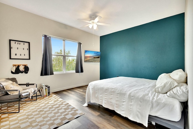 bedroom featuring ceiling fan, baseboards, and wood finished floors