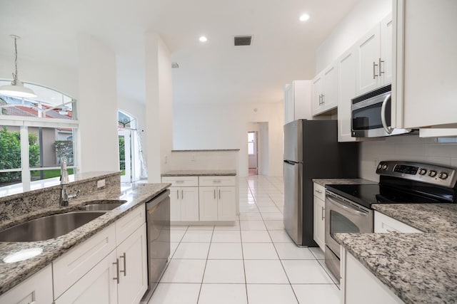 kitchen with appliances with stainless steel finishes, white cabinetry, a sink, and decorative light fixtures