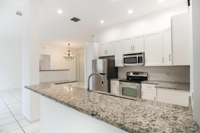 kitchen featuring visible vents, light stone counters, a peninsula, stainless steel appliances, and white cabinetry