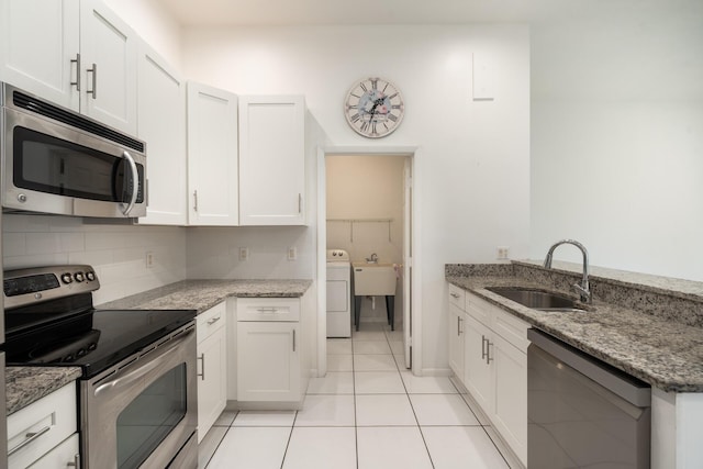 kitchen with appliances with stainless steel finishes, white cabinets, a sink, and light stone counters