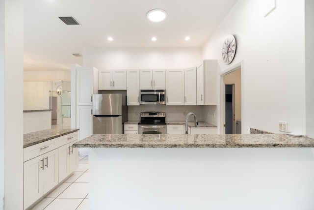 kitchen with visible vents, stainless steel appliances, light stone counters, and white cabinetry