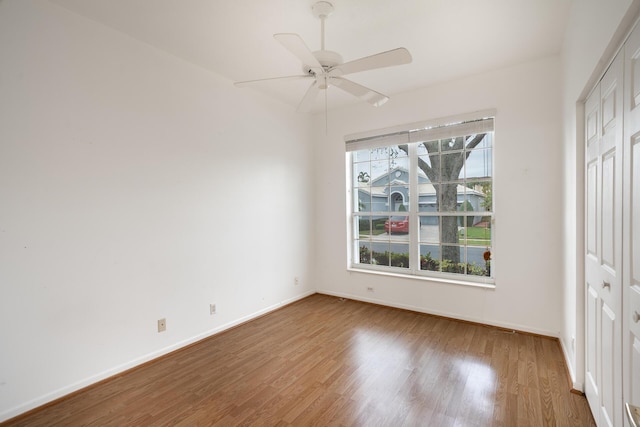 unfurnished bedroom featuring ceiling fan, a closet, baseboards, and wood finished floors