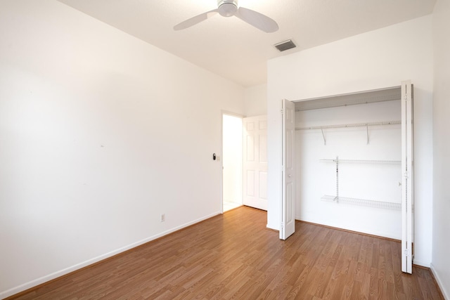 unfurnished bedroom featuring a closet, visible vents, a ceiling fan, wood finished floors, and baseboards