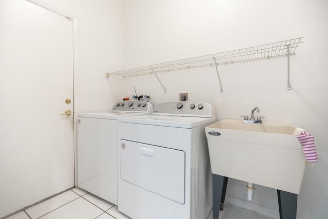 clothes washing area featuring light tile patterned floors, laundry area, a sink, and washer and dryer