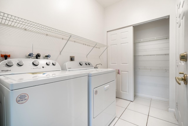 washroom featuring laundry area, light tile patterned floors, baseboards, and separate washer and dryer