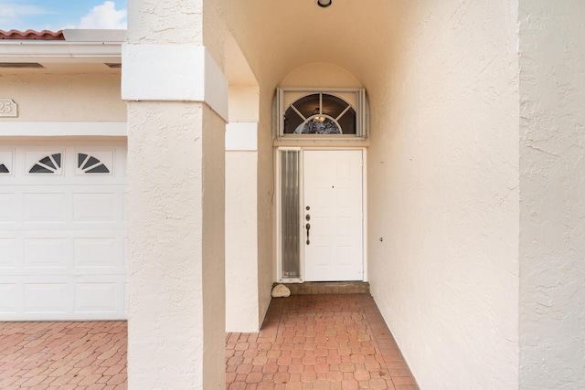 property entrance with a garage and stucco siding