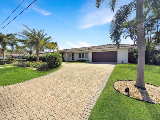 view of front of house with decorative driveway, a garage, a tiled roof, a front yard, and stucco siding