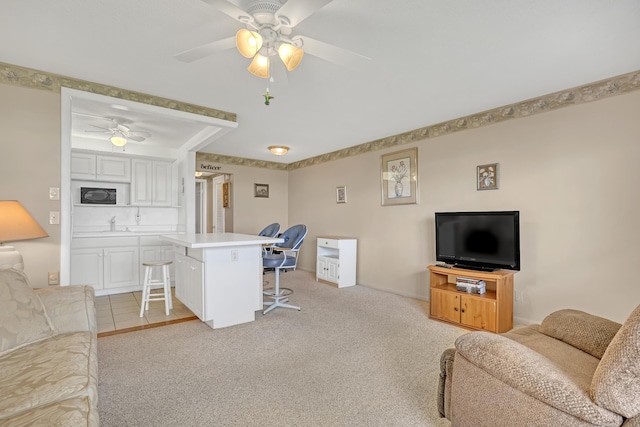 living room with sink, light colored carpet, and ceiling fan