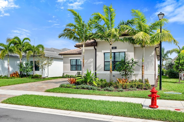 view of front of house featuring a front lawn, decorative driveway, and stucco siding