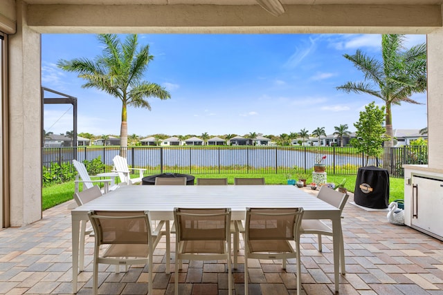 view of patio / terrace featuring outdoor dining space, a water view, and a fenced backyard