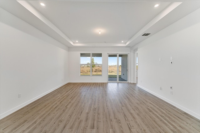unfurnished living room with a tray ceiling and light hardwood / wood-style floors