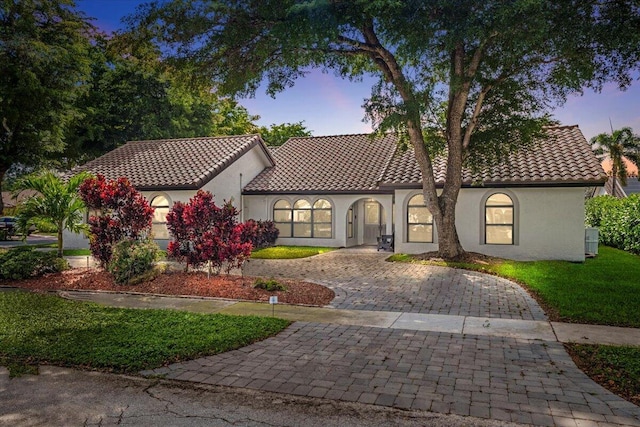 mediterranean / spanish-style house featuring driveway, a tile roof, and stucco siding