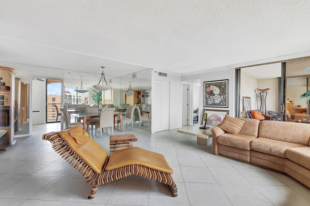 living room with a textured ceiling, light tile patterned flooring, and visible vents