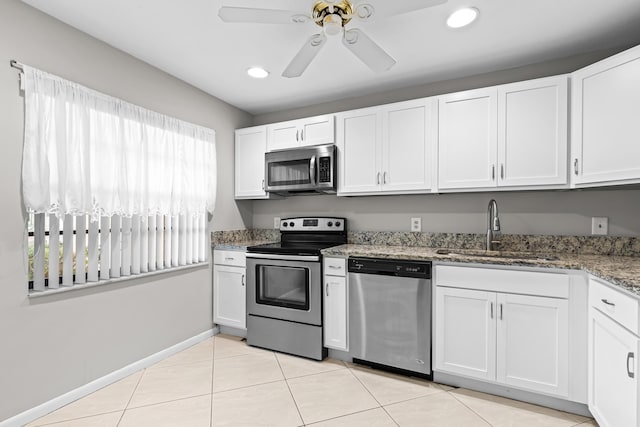 kitchen featuring appliances with stainless steel finishes, white cabinetry, sink, dark stone counters, and ceiling fan