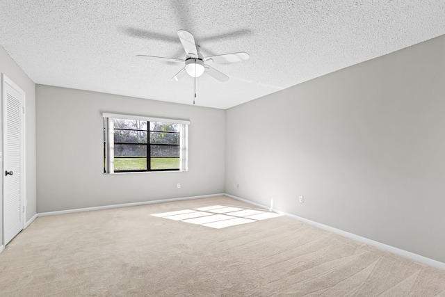 spare room with light colored carpet, a textured ceiling, and ceiling fan