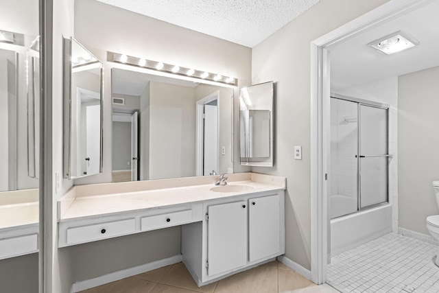 full bathroom with tile patterned floors, toilet, bath / shower combo with glass door, a textured ceiling, and vanity