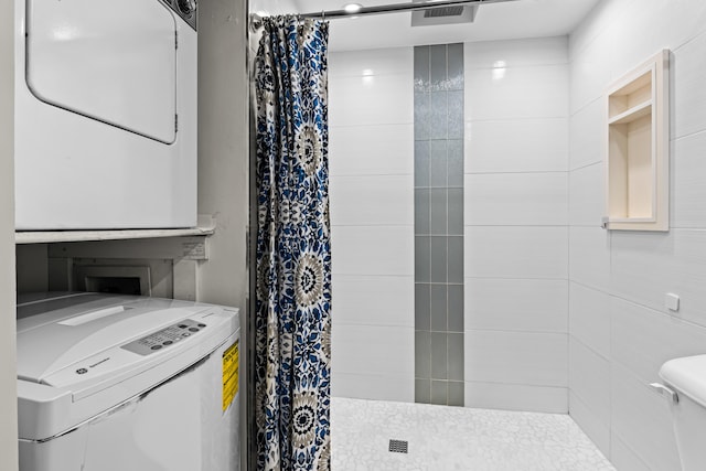 bathroom with stacked washer and dryer, toilet, and a shower with shower curtain