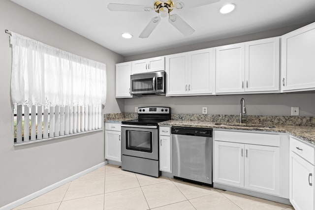 kitchen with sink, dark stone countertops, white cabinets, ceiling fan, and stainless steel appliances