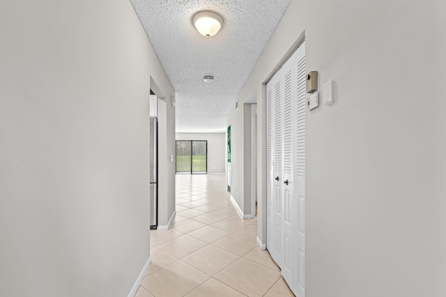 hallway with light tile patterned floors and a textured ceiling