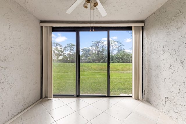 interior space featuring expansive windows, plenty of natural light, a textured ceiling, and ceiling fan