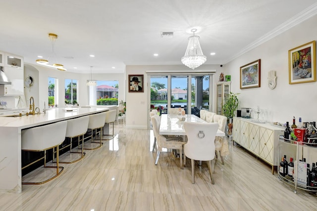 dining space featuring crown molding, sink, and an inviting chandelier