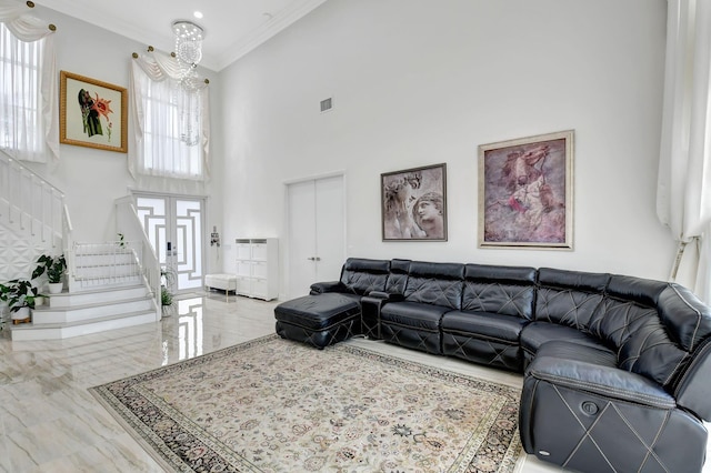 living room featuring ornamental molding, a towering ceiling, and an inviting chandelier