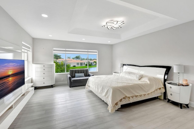 bedroom featuring a tray ceiling and light hardwood / wood-style floors