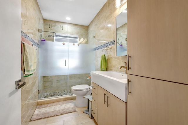 bathroom with tile walls, tile patterned flooring, vanity, an enclosed shower, and toilet