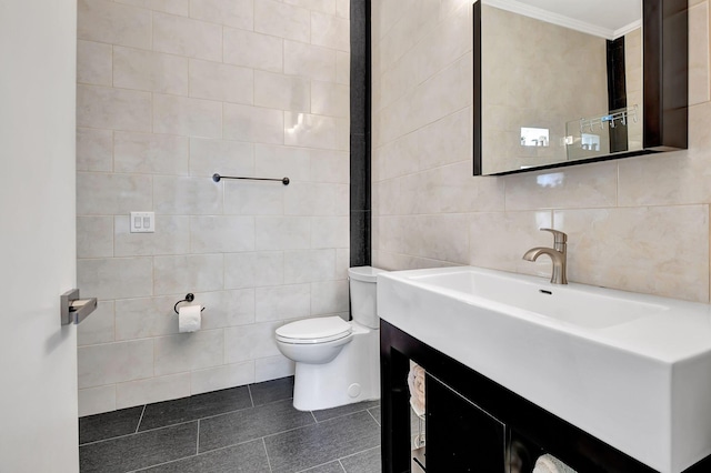 bathroom with tile patterned floors, toilet, crown molding, tile walls, and vanity