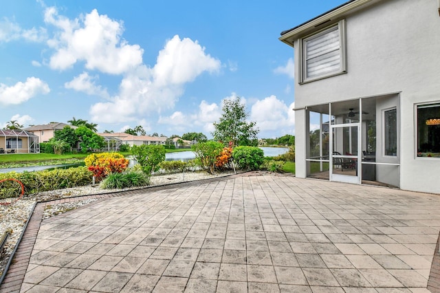 view of patio with a sunroom, ceiling fan, and a water view