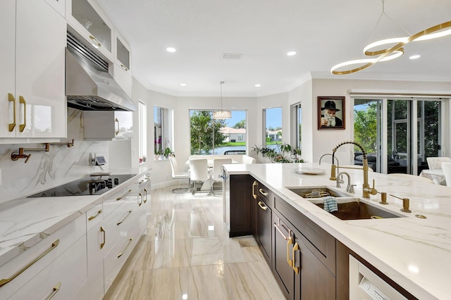 kitchen with black electric cooktop, sink, decorative light fixtures, and white cabinets