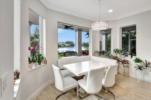 dining space featuring ornamental molding, a water view, and a chandelier