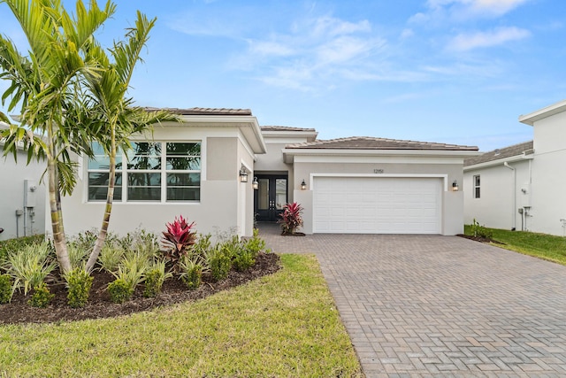 prairie-style home featuring stucco siding, an attached garage, and decorative driveway