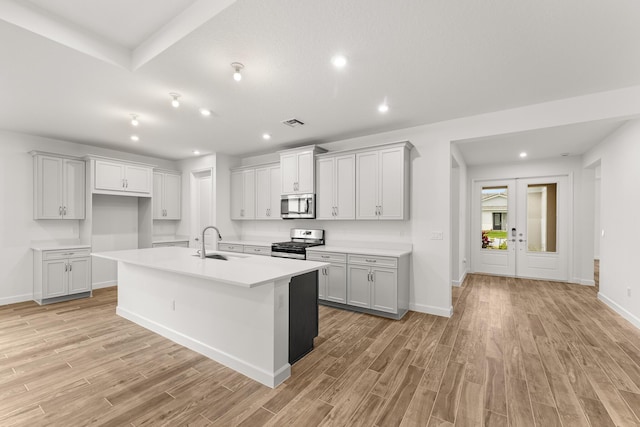 kitchen with a kitchen island with sink, visible vents, appliances with stainless steel finishes, and light wood-type flooring