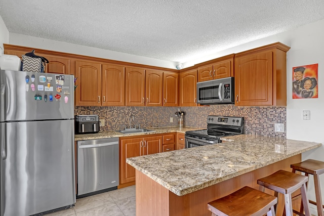 kitchen with stainless steel appliances, a sink, a peninsula, and a kitchen breakfast bar