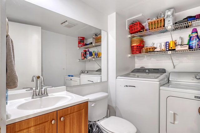 bathroom with toilet, separate washer and dryer, and vanity