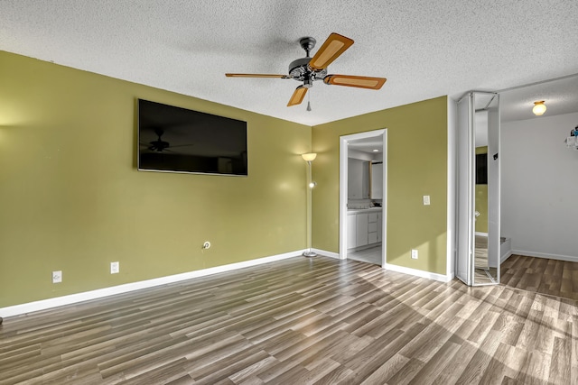 unfurnished living room with a textured ceiling, wood finished floors, a ceiling fan, and baseboards