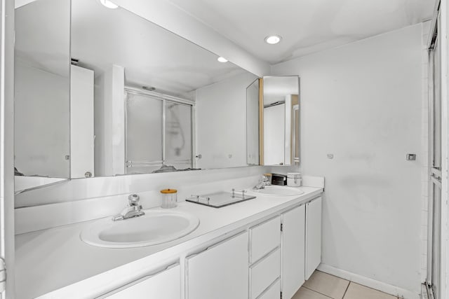 full bathroom with double vanity, a stall shower, a sink, and tile patterned floors