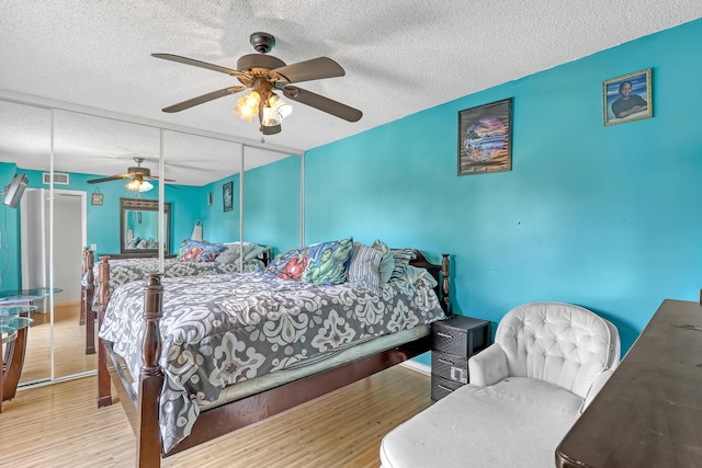 bedroom featuring a textured ceiling, a closet, wood finished floors, and a ceiling fan